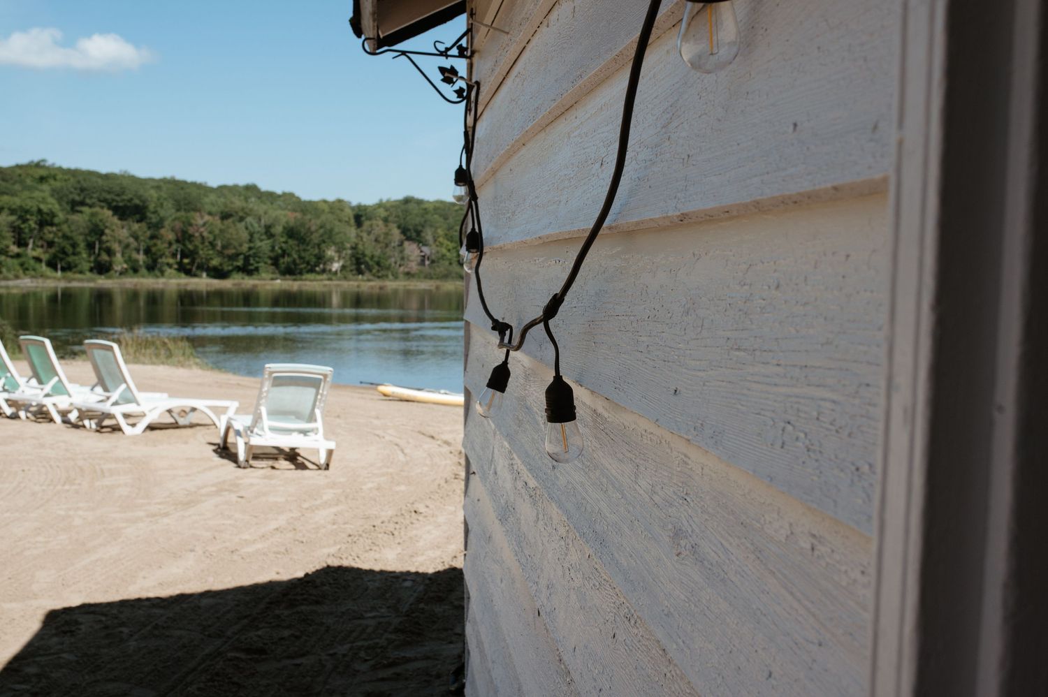 A lakeside scene with white lounge chairs and a white building exterior.