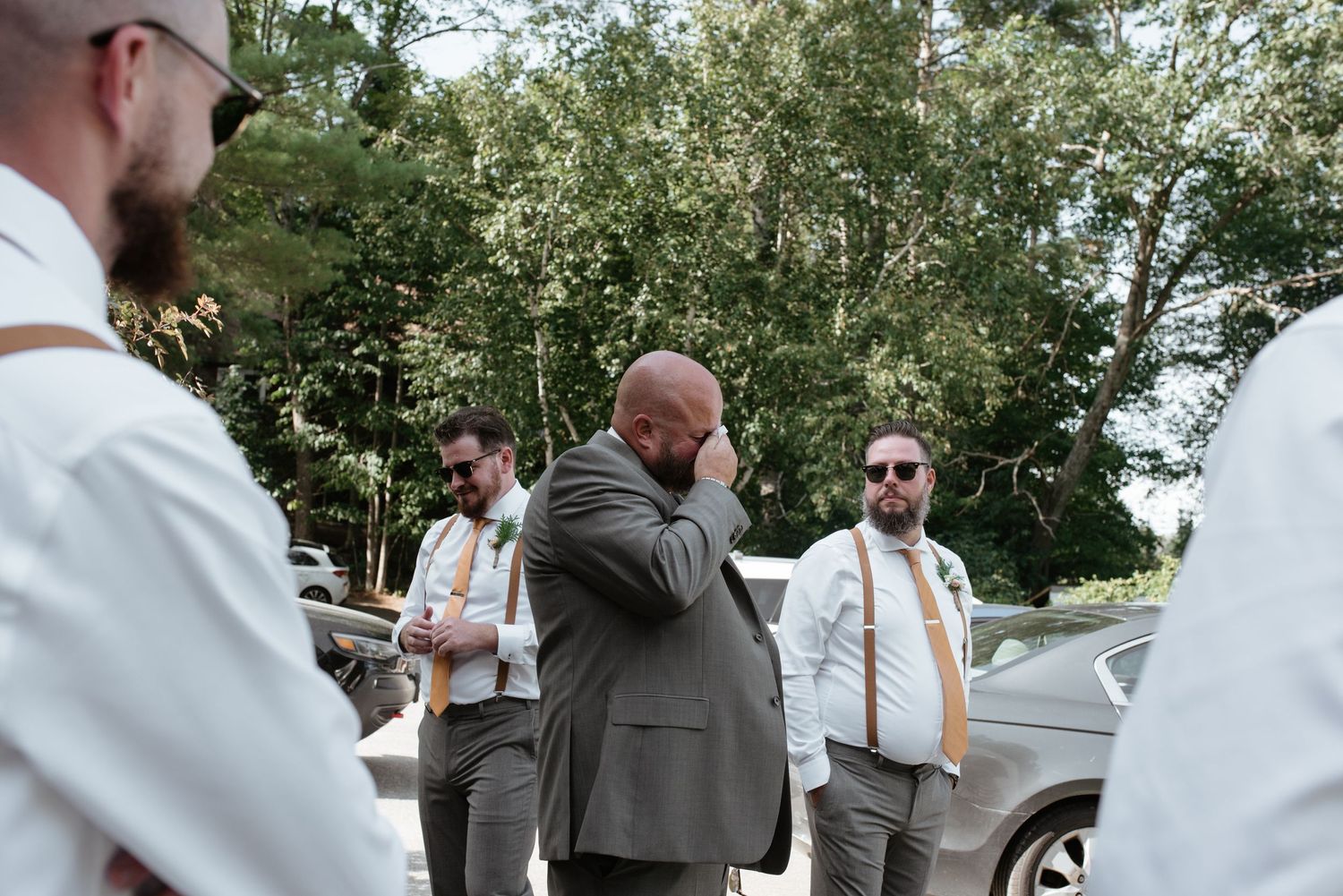 Wedding party in formal attire gathered outdoors with emotional reactions.