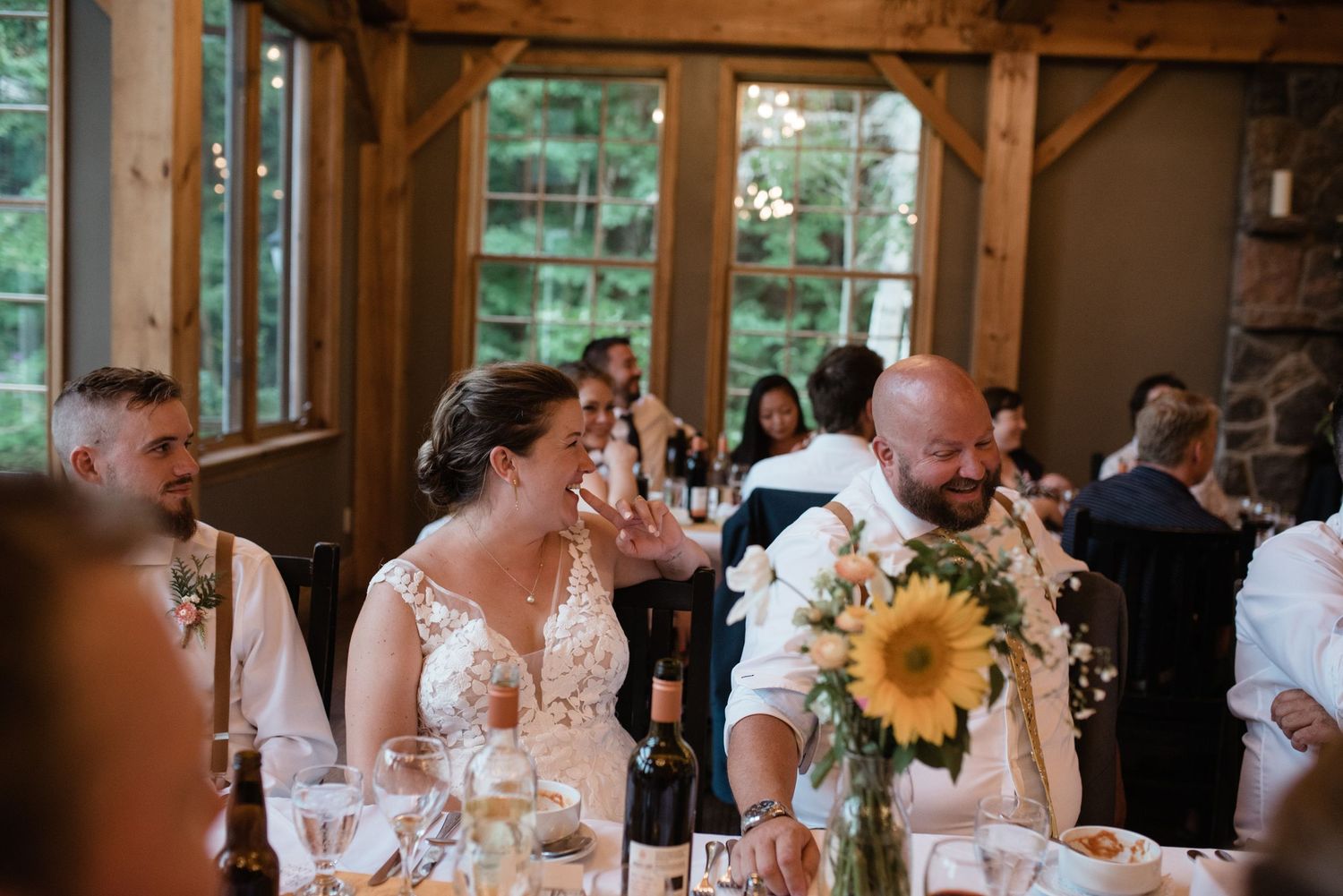 Wedding reception in a rustic wooden venue with sunflowers decorating the dining tables.