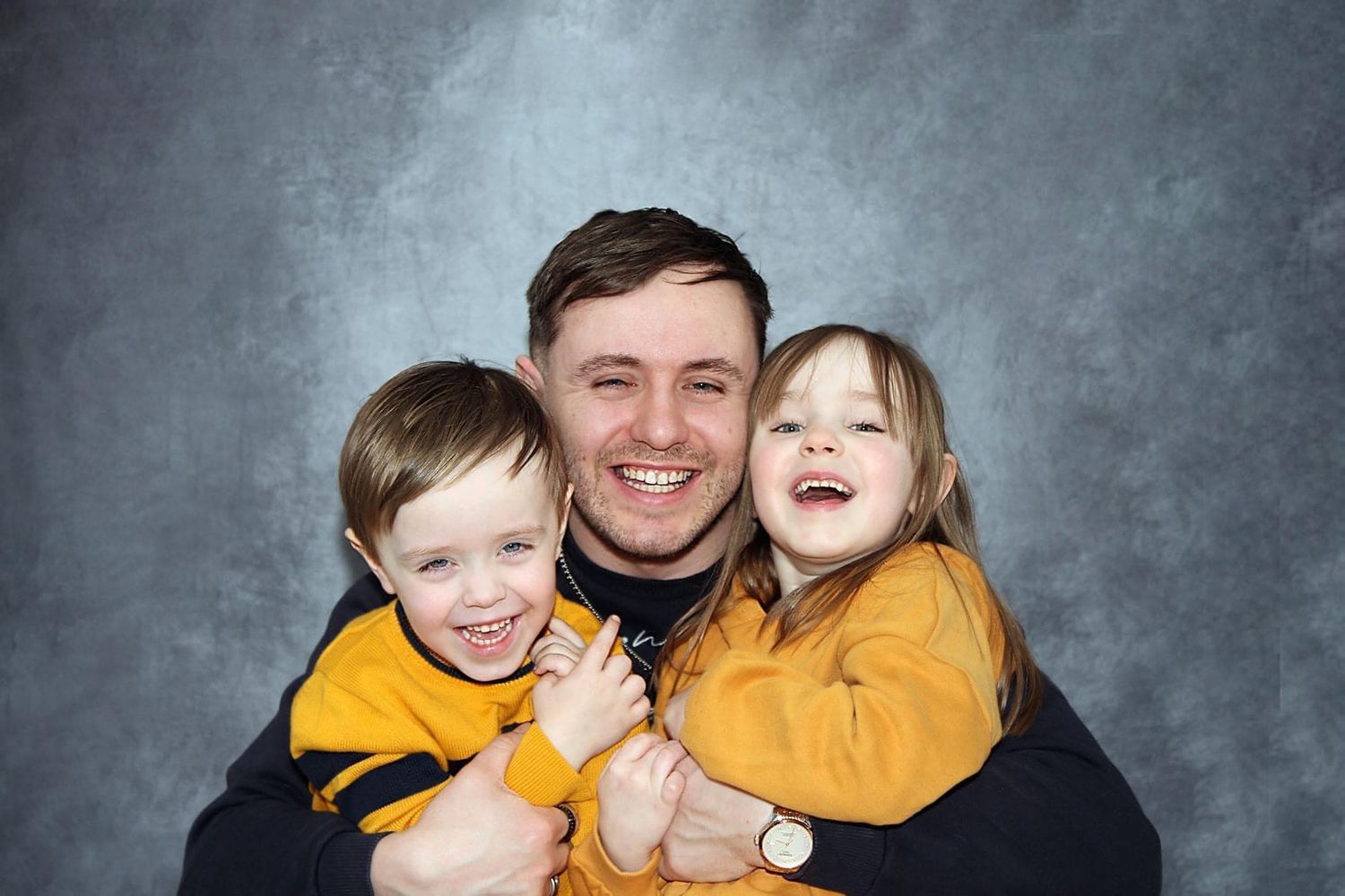 Professional studio portrait session against grey backdrop.