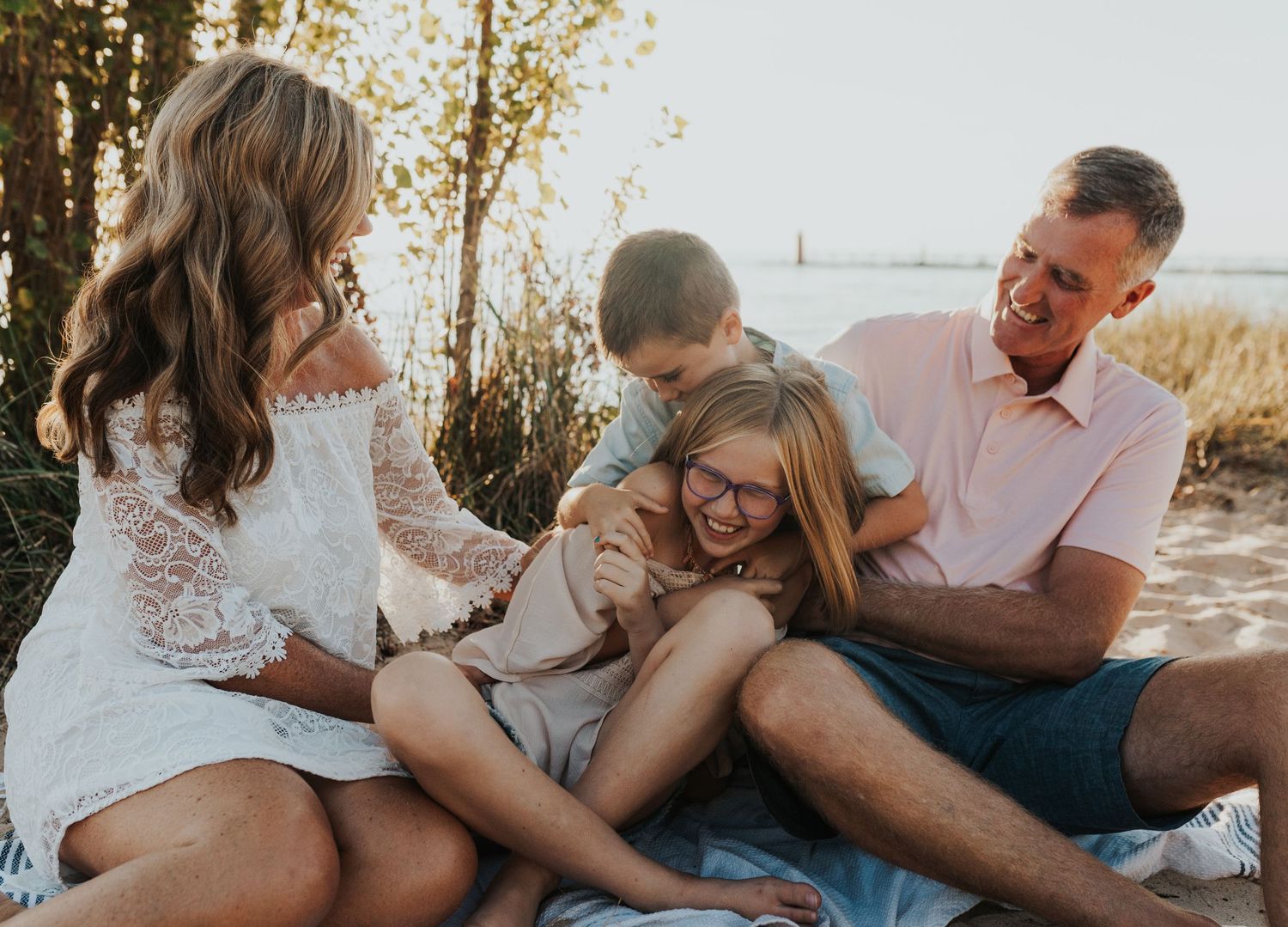 Family close together laughing on the beach in South Haven Michigan