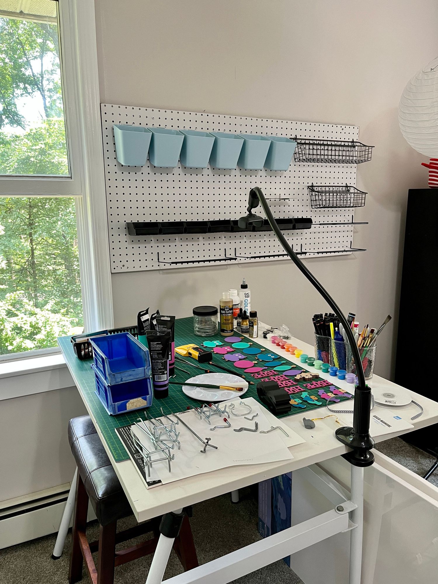 Photo of middle stage of organizing art studio table and supplies using a pegboard.