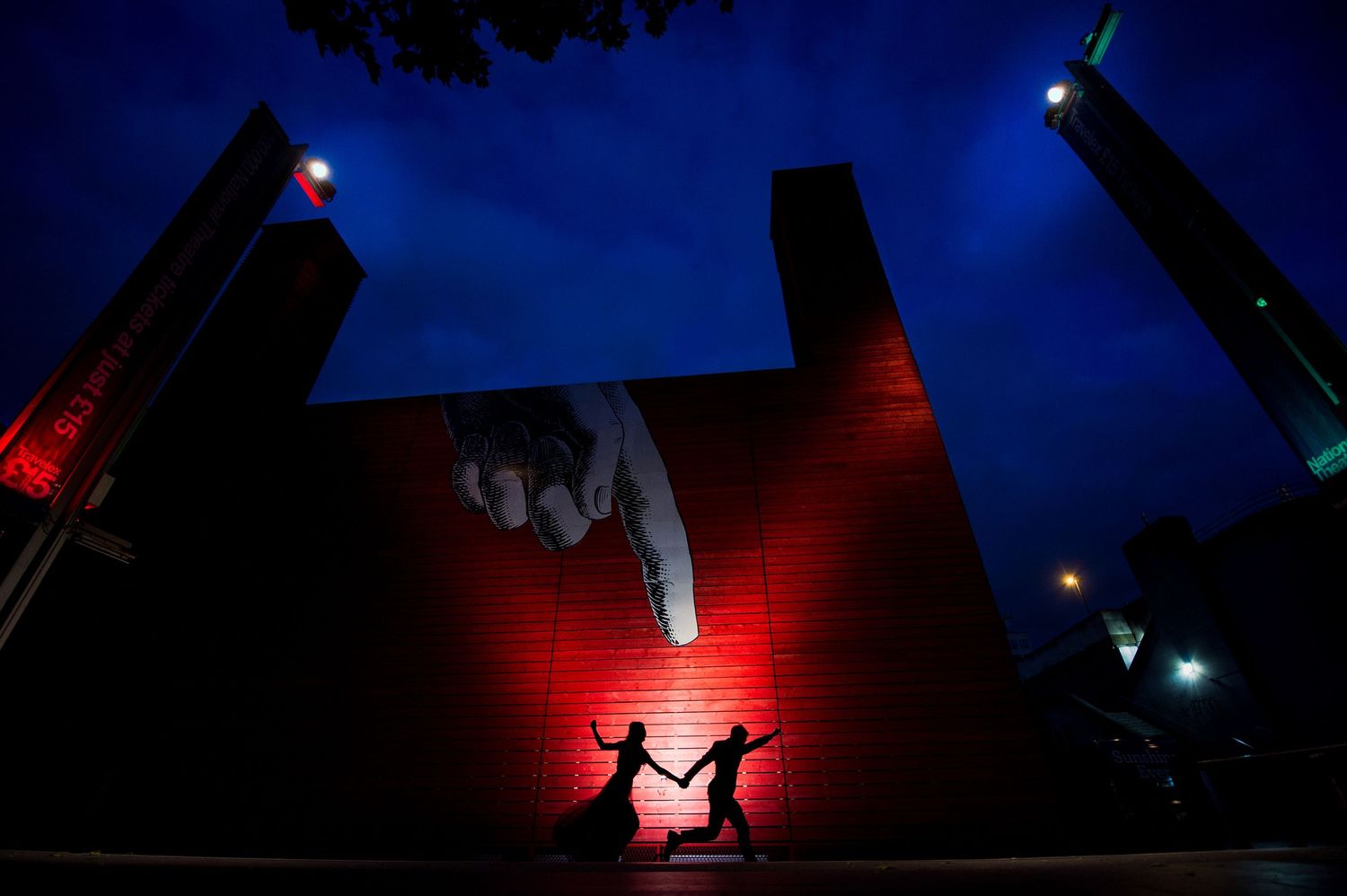 Playful shot of couple dancing in silhouette near Globe Theatre