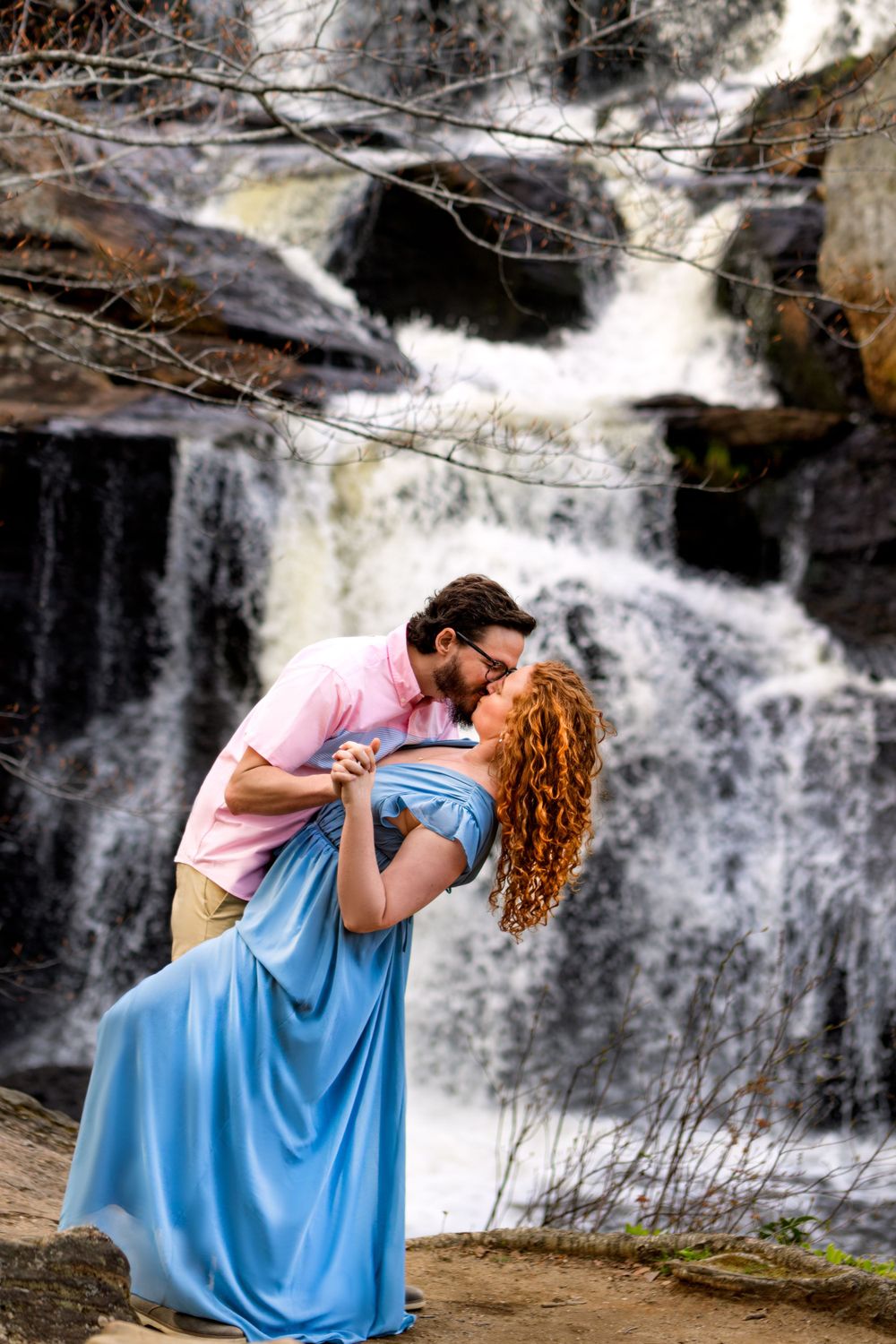 A romantic dip pose in front of a cascading waterfall with a flowing blue dress.