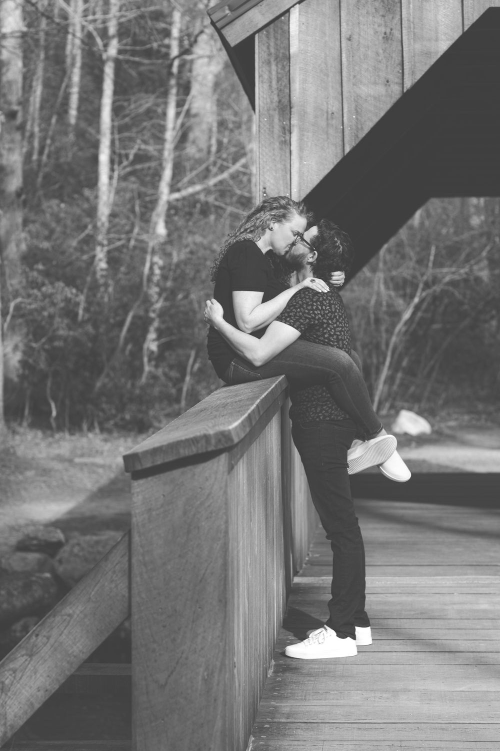 A romantic black and white moment shared on a wooden deck railing.