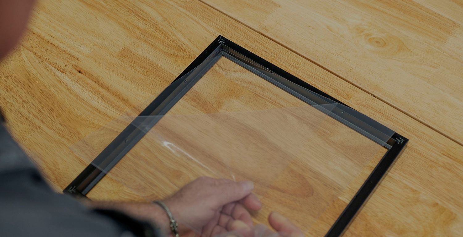 Hand placing or adjusting black frame on wooden surface in closeup view.