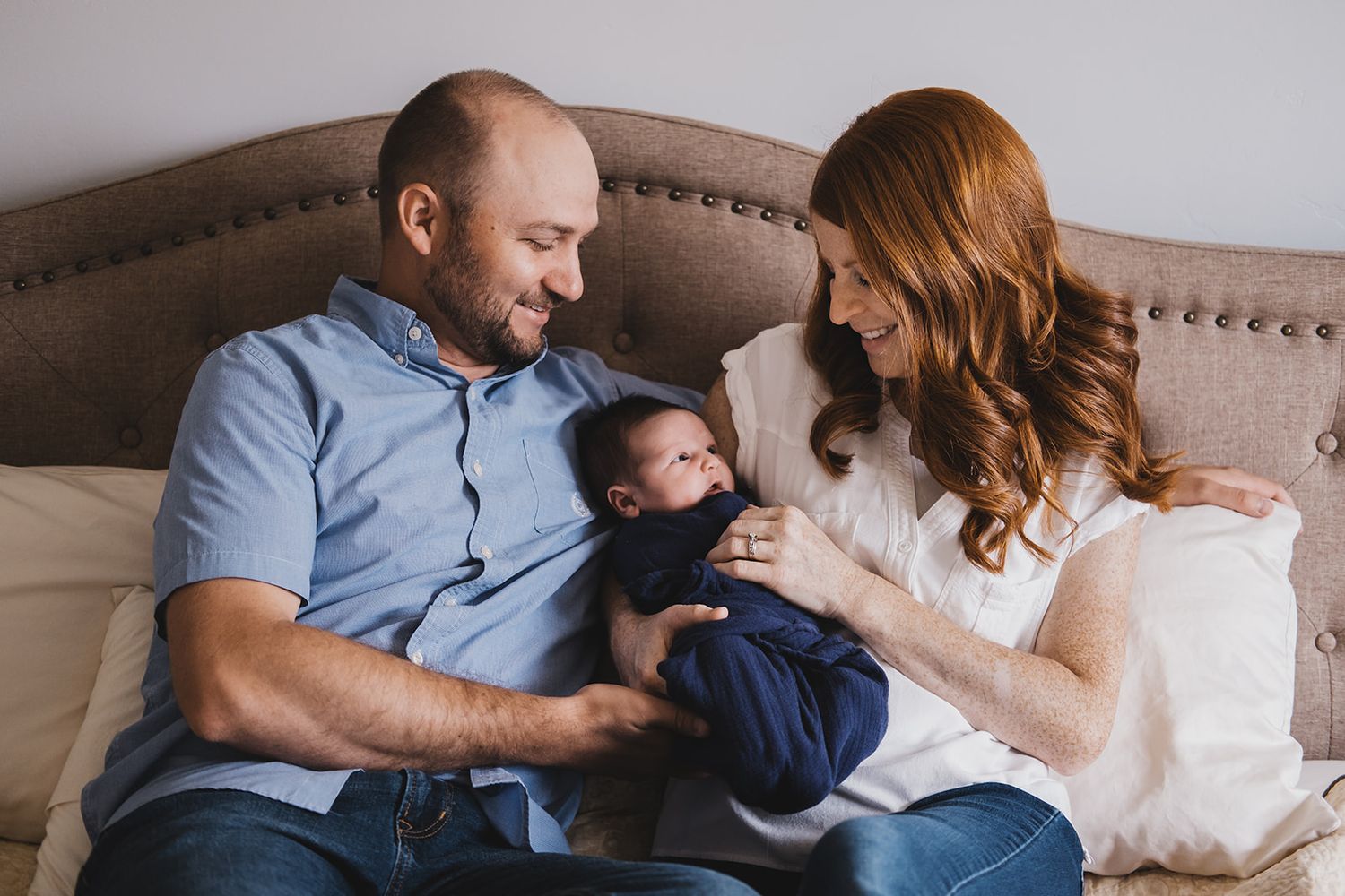 mom, dad, and newborn baby on their bed in Farmington, Utah Davis County.