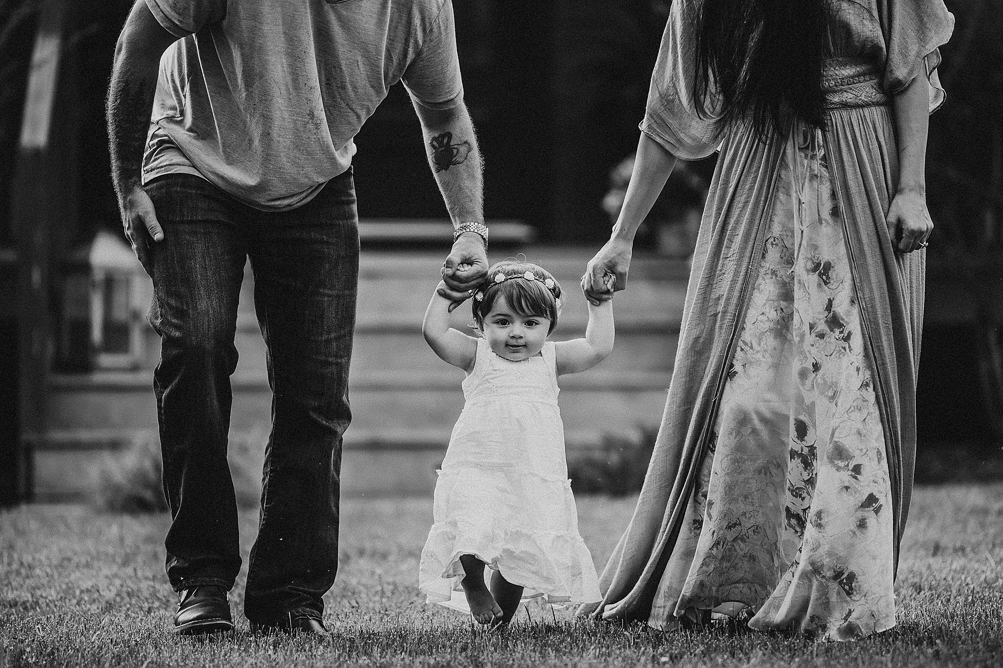 Black and white photo of a family walking together on grass, holding hands.