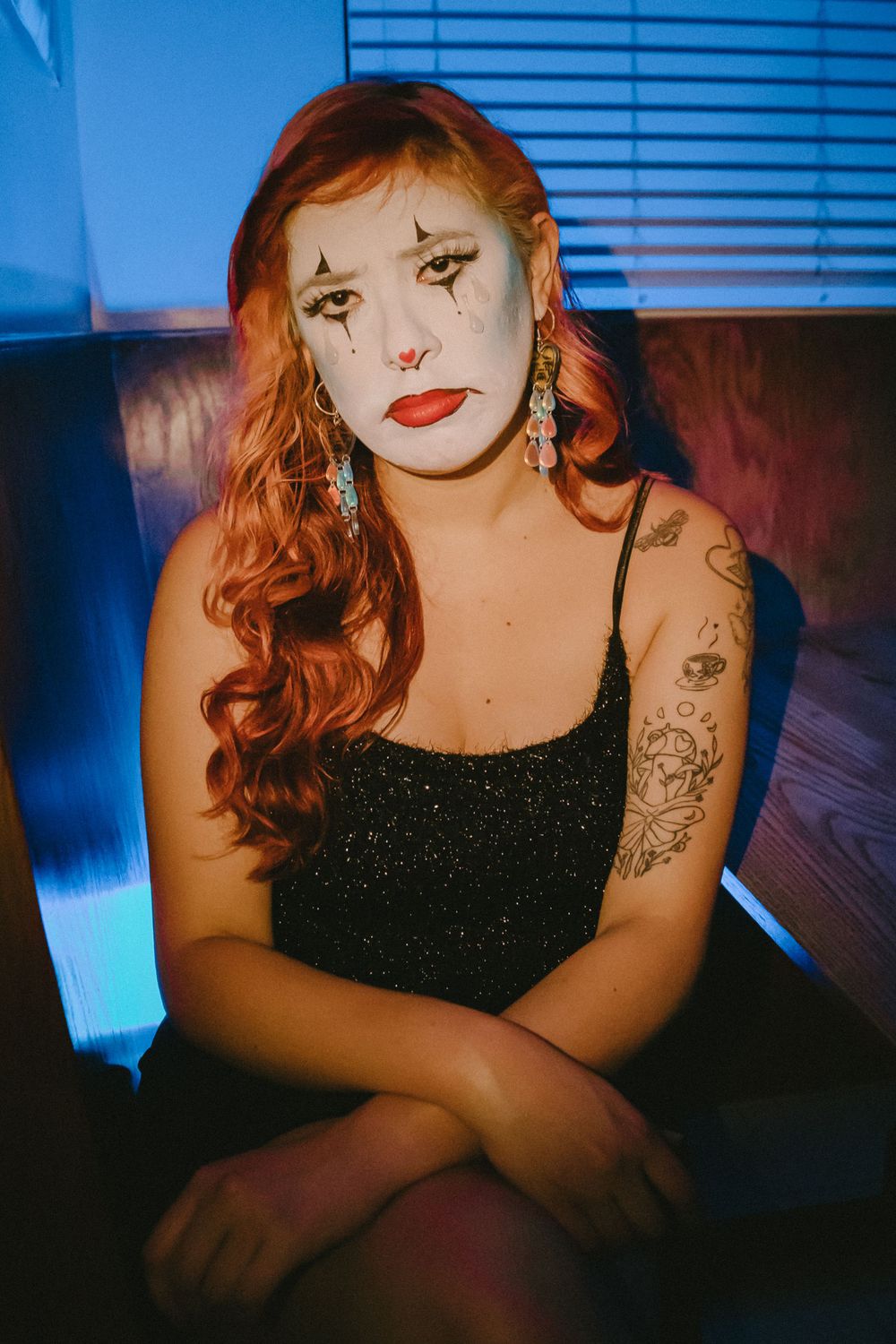 Portrait with sparkly black top and dramatic makeup against dark blue background.