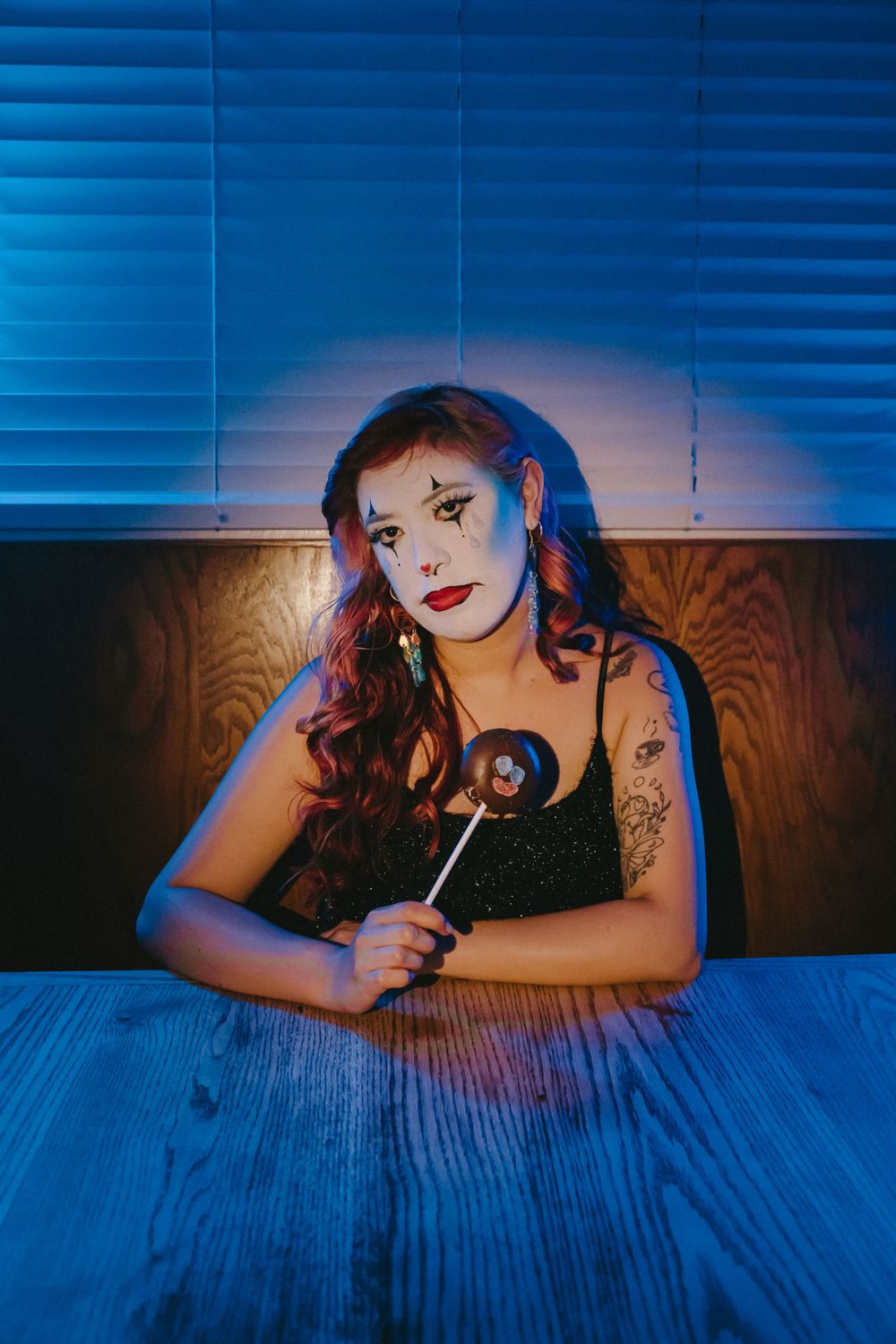 Moody portrait with dramatic blue lighting showing theatrical makeup and a black tank top.
