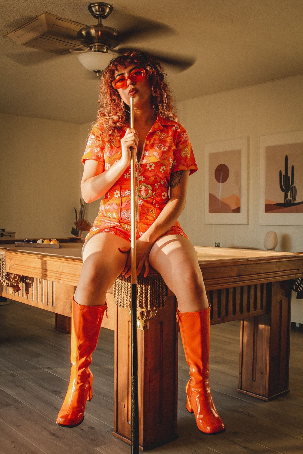 Retro-styled shoot on pool table with bright orange fashion and matching boots.