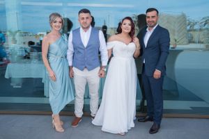 Wedding party in coordinated blue and white attire poses together outdoors.