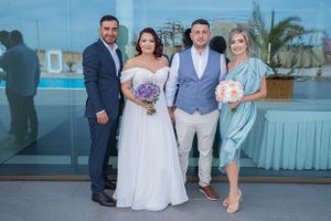 Wedding party members pose together outdoors with palm trees visible in background.