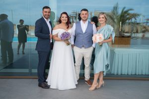 Wedding group photo with bride in white dress and attendants in formal attire.
