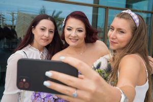 Wedding party members in purple and white dresses share joyful moments together during outdoor photo session.