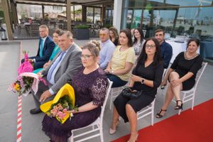 Wedding guests seated in white chairs during outdoor ceremony.