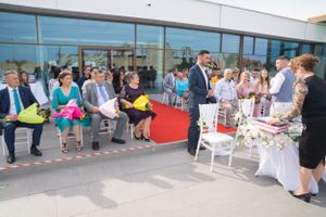 Wide view of wedding venue setup with guests seated along red carpet aisle.