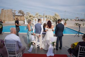 Panoramic view of outdoor wedding ceremony with guests seated under blue sky.