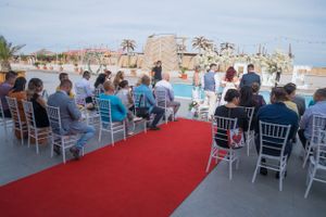 Wedding ceremony setup with red carpet aisle and white chairs overlooking scenic venue.