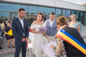 Wedding ceremony participants gather outside modern building with glass facade.