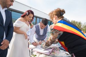 Wedding party members sign official documents during outdoor ceremony.
