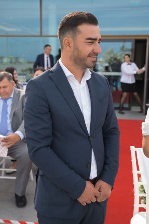 Groom in navy suit stands on red carpet during wedding ceremony.