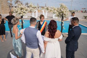 Wedding guests mingle during outdoor reception near pool area.
