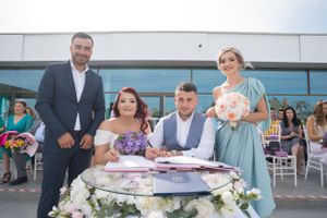 Wedding party gathered outside modern building for document signing ceremony.
