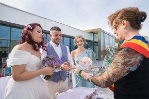 Outdoor wedding celebration with guests watching document signing ceremony.