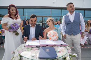 Wedding party gathered around table during outdoor signing ceremony.