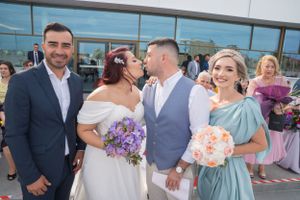 Outdoor wedding celebration with guests and floral arrangements near modern building.