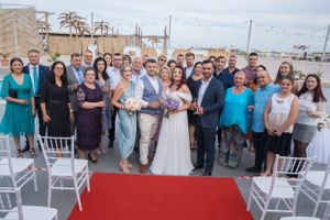 Wide view of wedding celebration with white chairs and guests gathered outdoors.