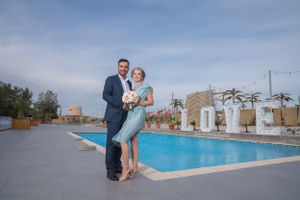 Wedding celebration at an outdoor venue with swimming pool and decorative palm trees.