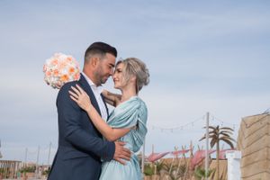 Couple shares intimate moment during outdoor wedding photoshoot by pool.