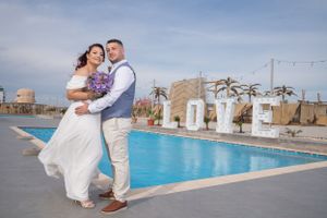 A romantic beachside photo session with a swimming pool and palm trees in the background.