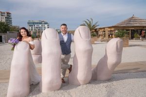 White sculptural seating elements line a beachfront promenade under blue skies.