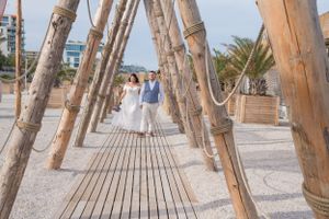 Rustic wooden poles create an artistic walkway structure on a sandy beach.