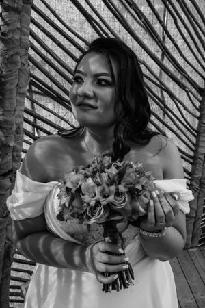 Black and white portrait with bride holding floral bouquet against geometric background.