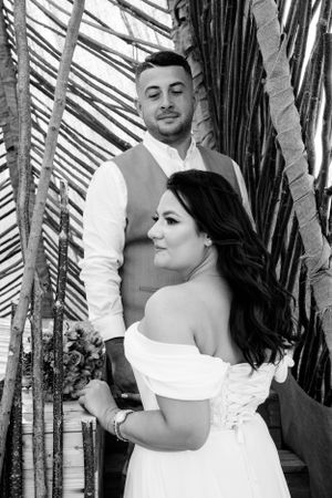 Black and white wedding portrait with couple against diagonal bamboo pattern.