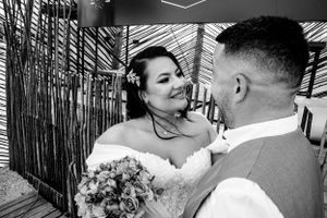 Intimate black and white wedding moment captured against bamboo wall.