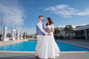 Wedding photo session featuring a couple in white against a bright blue pool and sky backdrop.
