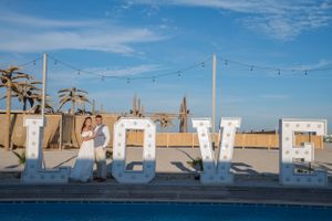 Outdoor wedding venue with string lights and palm trees against a vibrant blue sky.