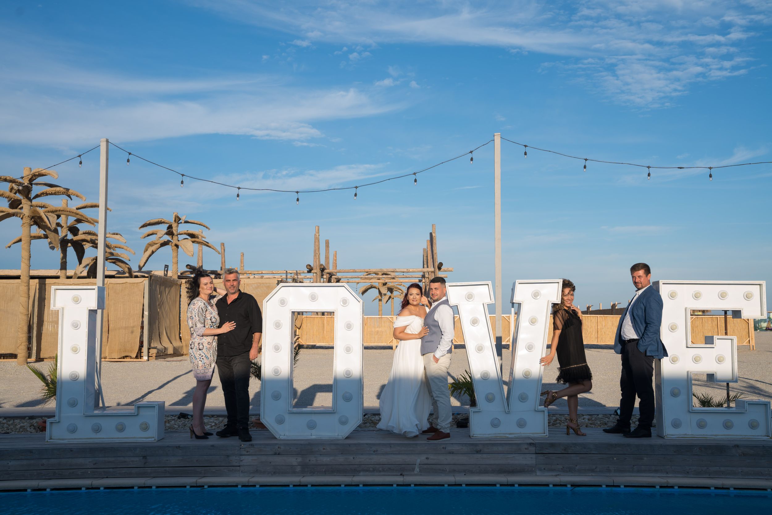 Outdoor rooftop wedding ceremony setup against a bright blue sky with string lights.