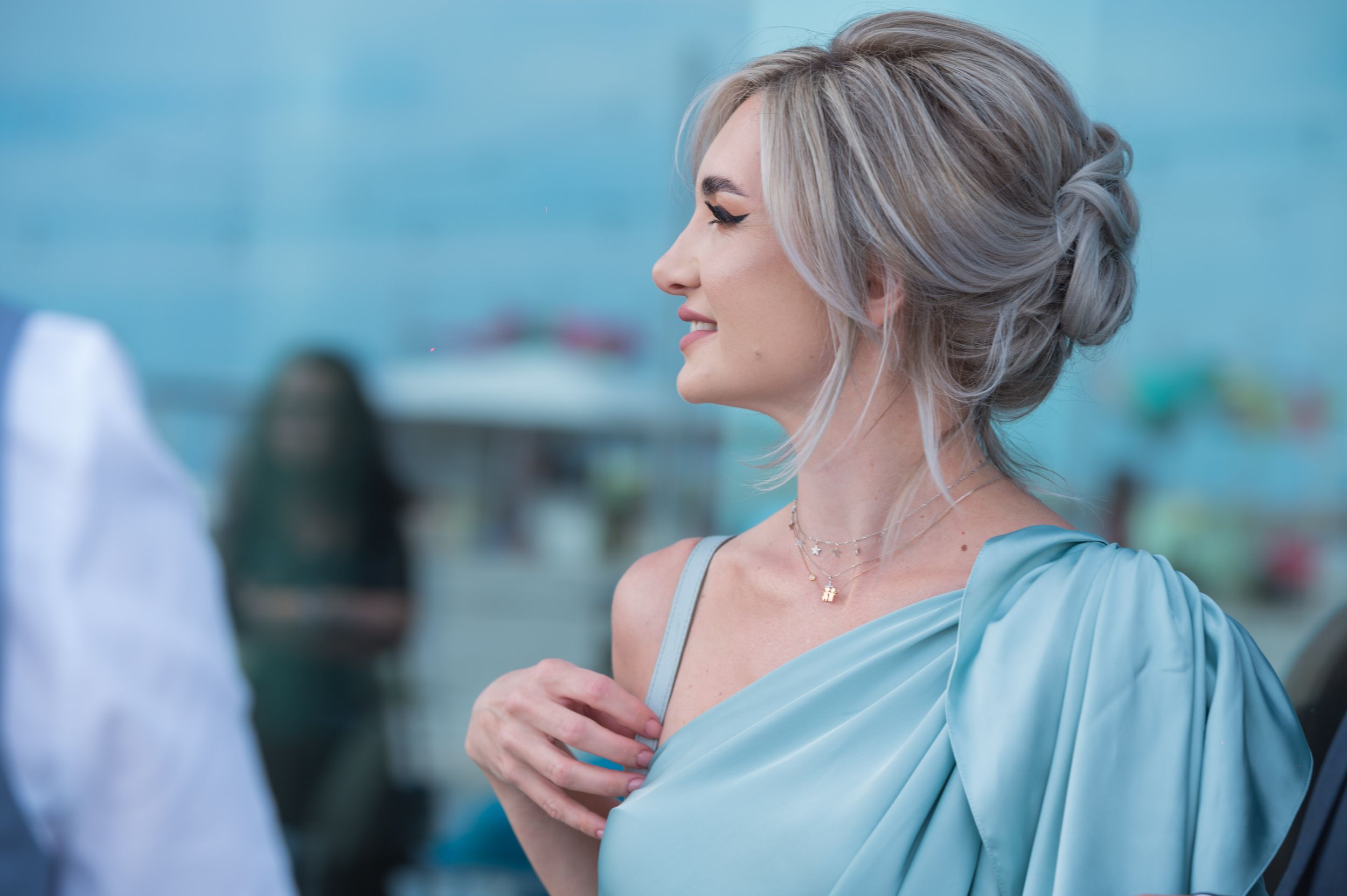 Wedding guests in formal attire mingling at an outdoor reception with blue backdrop.