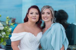 Wedding party members in light blue and white formal attire gather for outdoor photos.