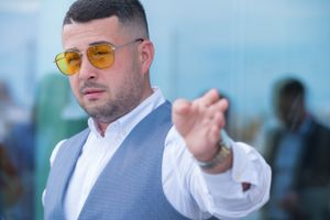 Groomsmen in sunglasses and formal attire pose outdoors at a beach wedding venue.