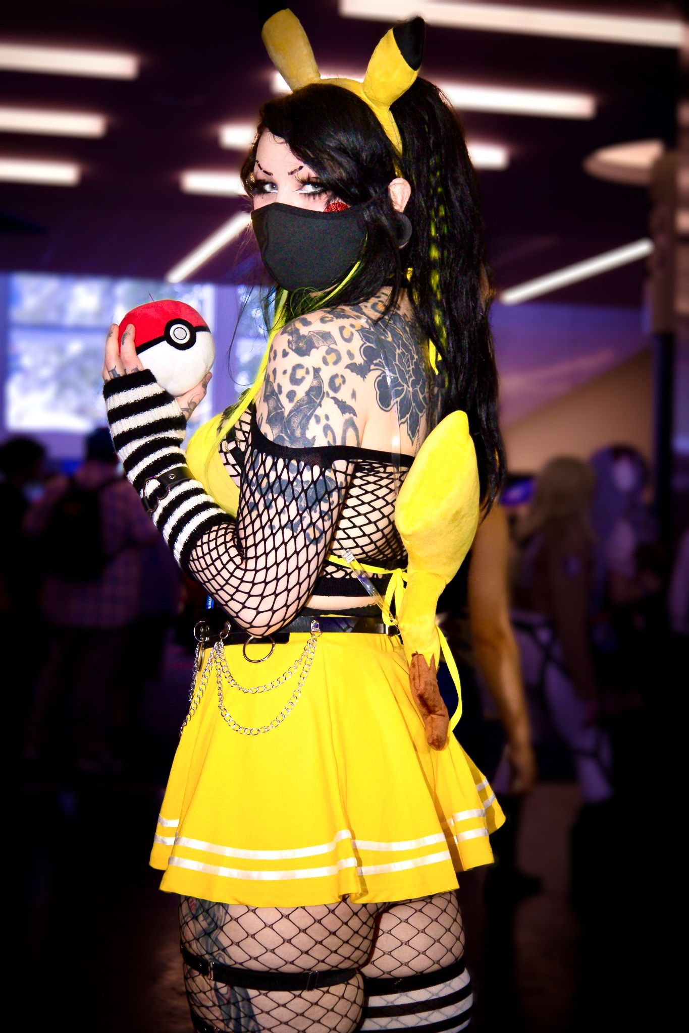 Pokemon-inspired cosplay featuring yellow dress, fishnet stockings and Pokeball accessory.