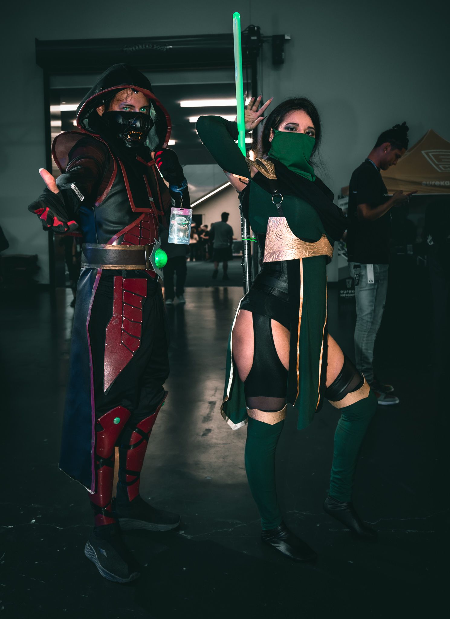 Ninja-themed cosplayers wielding glowing lightsabers in dramatic low-light setting.