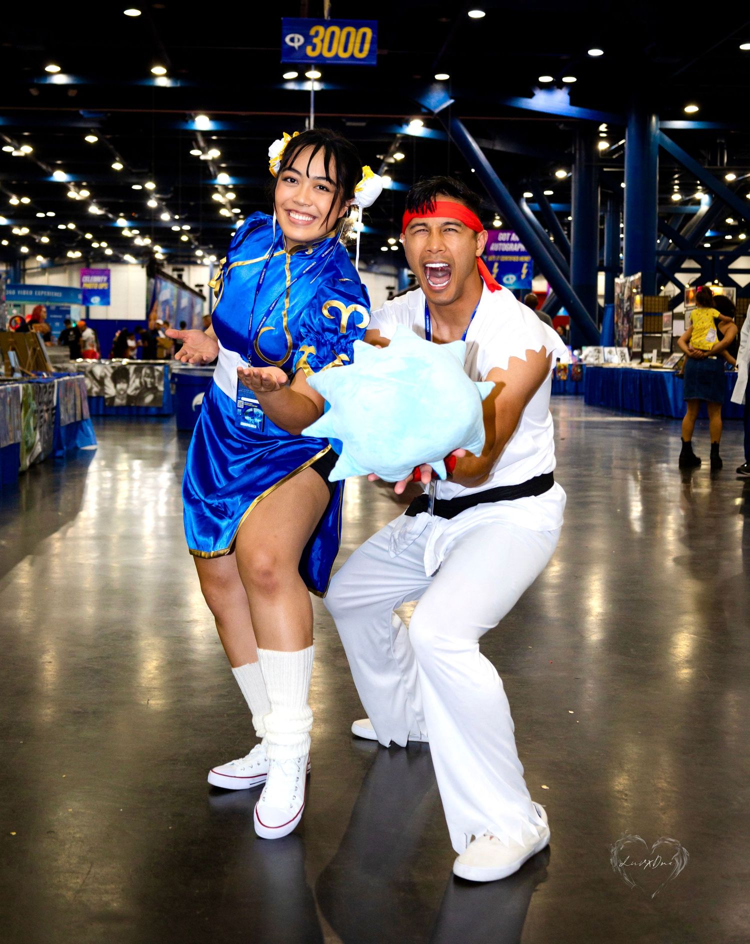 Street Fighter Chun-Li and Ryu cosplayers performing dynamic fighting poses at convention.