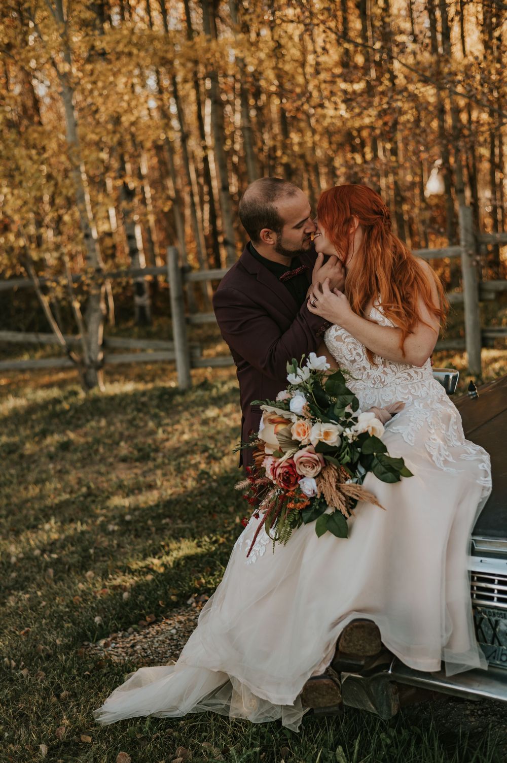 Intimate wedding portrait in a golden autumn forest with a classic vintage car.